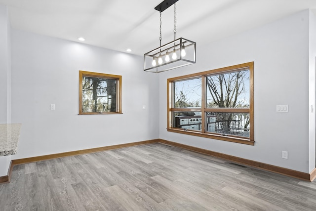 unfurnished dining area with visible vents, wood finished floors, and baseboards