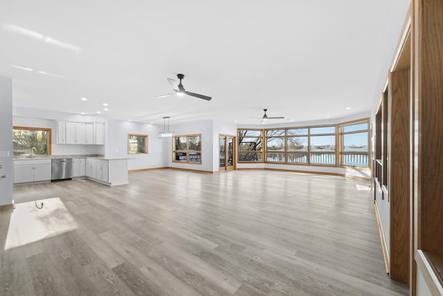 unfurnished living room featuring baseboards, recessed lighting, light wood-type flooring, and a sink