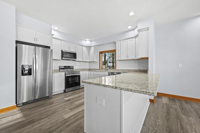 kitchen with dark wood-type flooring, backsplash, appliances with stainless steel finishes, and a peninsula