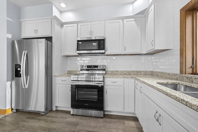 kitchen featuring backsplash, appliances with stainless steel finishes, dark wood finished floors, and white cabinetry