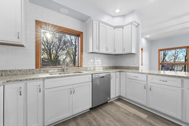 kitchen with a sink, backsplash, stainless steel dishwasher, wood finished floors, and white cabinetry