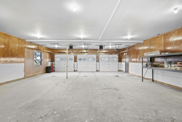 garage with a garage door opener and wood walls