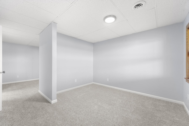 finished below grade area featuring visible vents, carpet, baseboards, and a drop ceiling