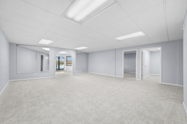 basement with arched walkways, a drop ceiling, and carpet floors