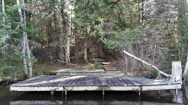 view of dock with a wooded view and a water view