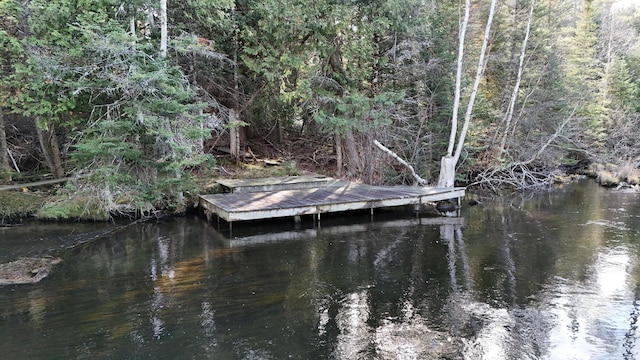 view of dock featuring a forest view and a water view