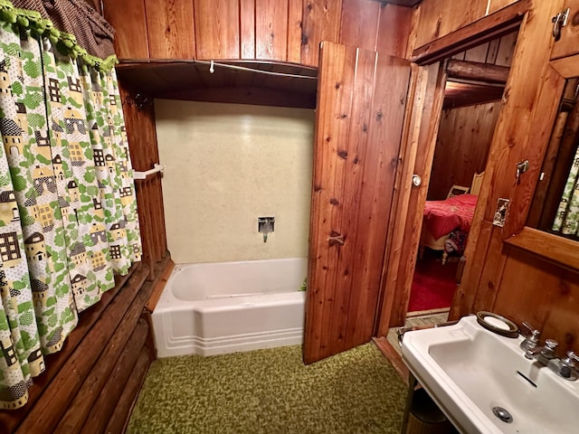 bathroom with a bath, wood walls, and a sink