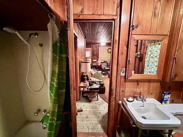 bathroom featuring shower / bath combination with curtain, wood ceiling, wood walls, and a sink