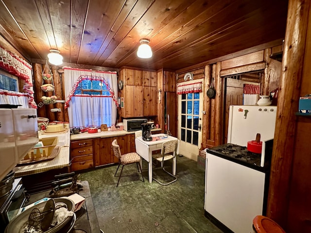 kitchen with wooden ceiling, wooden walls, brown cabinets, and freestanding refrigerator