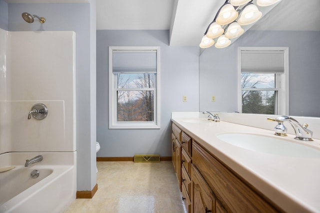 bathroom with a sink, baseboards, toilet, and tub / shower combination