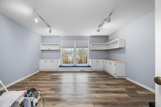 interior space featuring track lighting, baseboards, and dark wood-style flooring