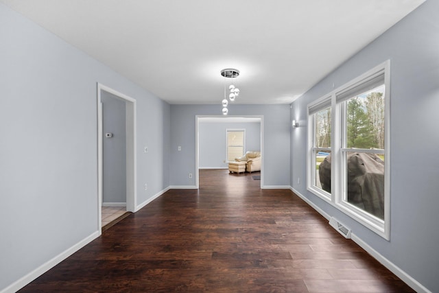 hall with dark wood-style floors, visible vents, and baseboards