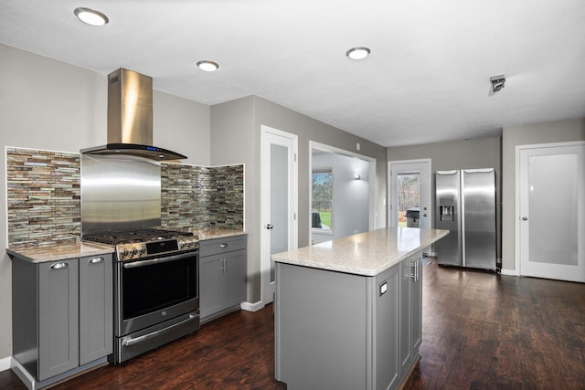 kitchen with dark wood-style floors, gray cabinets, stainless steel appliances, and wall chimney range hood