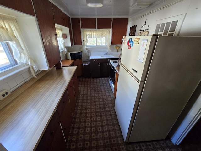 kitchen featuring white appliances, light countertops, dark floors, and a sink