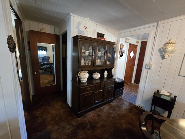 corridor with ornamental molding and dark carpet