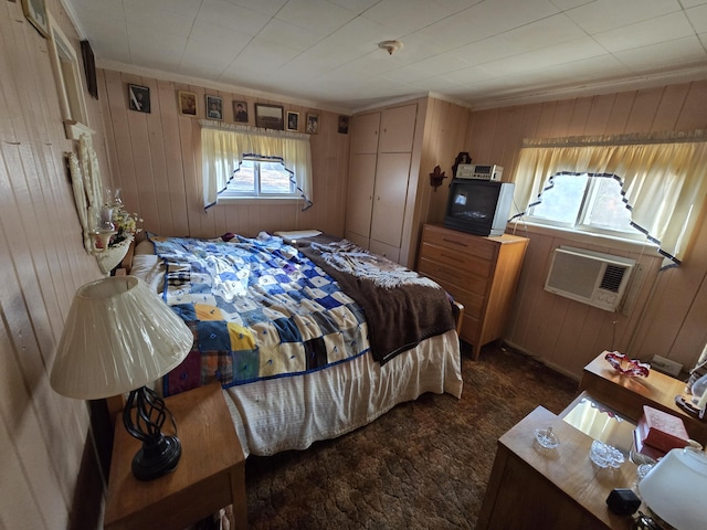 bedroom featuring dark colored carpet, multiple windows, and wood walls