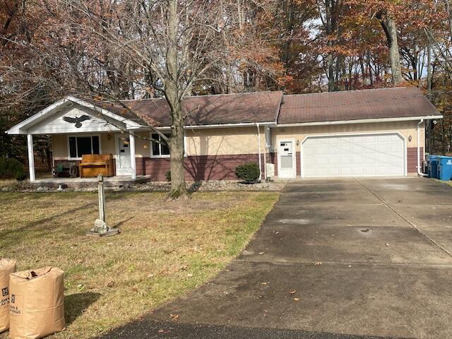 single story home with covered porch, driveway, a front yard, and a garage