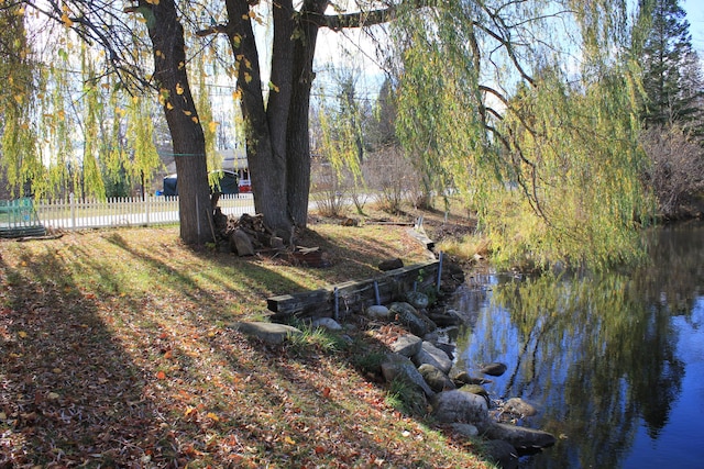 view of yard with a water view and fence