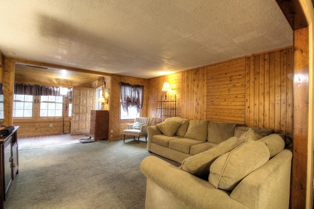 living area featuring carpet flooring, wood walls, and a textured ceiling