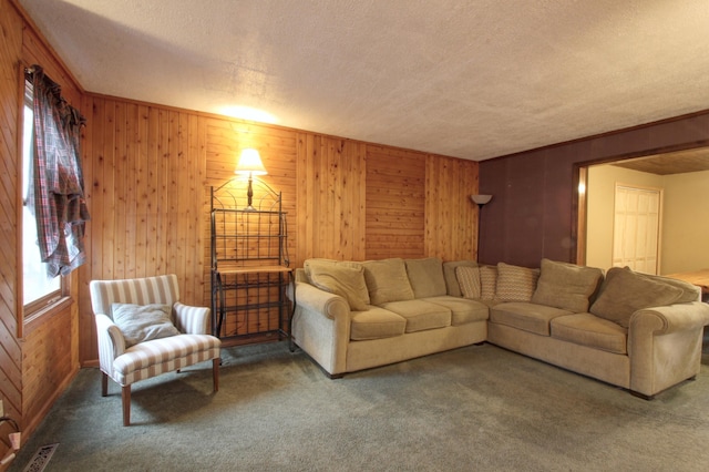 carpeted living room featuring visible vents, wood walls, a textured ceiling, and ornamental molding