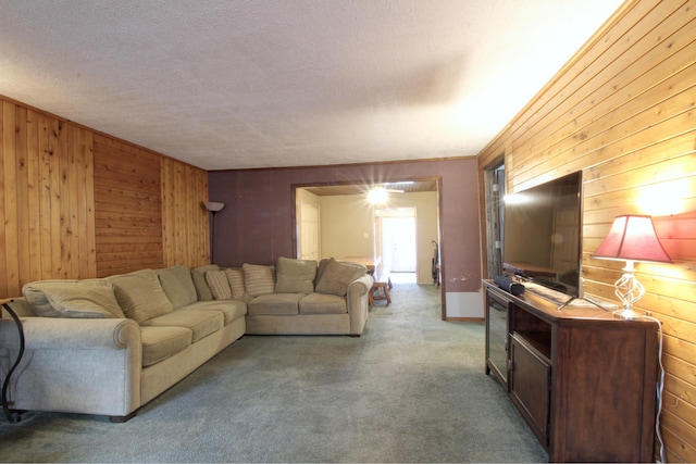 carpeted living room featuring wooden walls and a textured ceiling