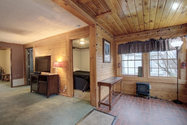 interior space featuring brick floor, wooden walls, wood ceiling, and a wood stove