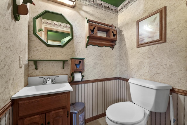 half bathroom with wallpapered walls, toilet, and vanity