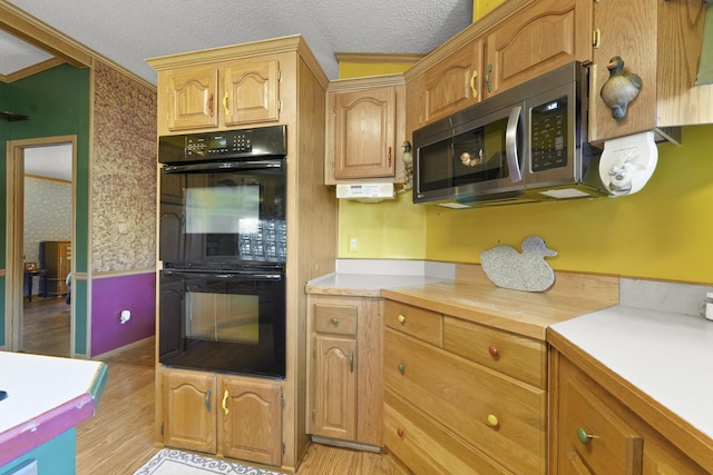 kitchen featuring light wood finished floors, light countertops, a textured ceiling, stainless steel microwave, and dobule oven black