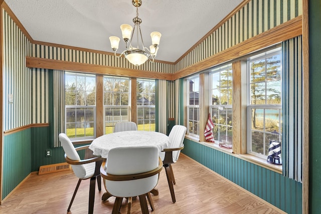 dining space with wallpapered walls, a notable chandelier, and a textured ceiling