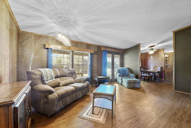 living room featuring a textured ceiling, wood finished floors, and ornamental molding