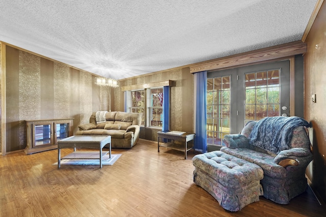 living room with a textured ceiling, an inviting chandelier, wood finished floors, and ornamental molding