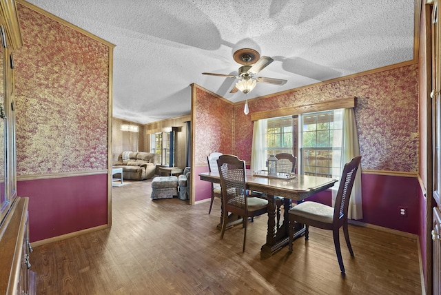 dining area featuring wainscoting, a textured ceiling, wallpapered walls, and wood finished floors