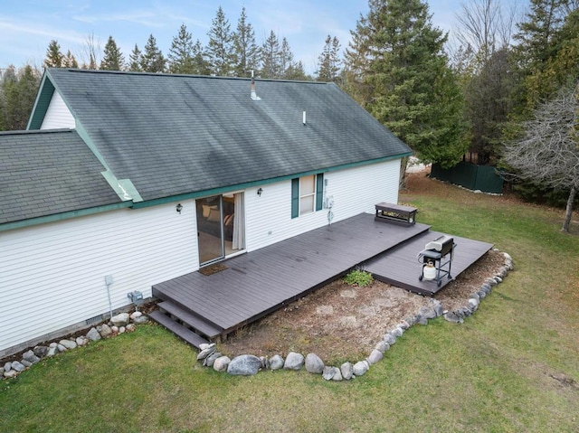 rear view of house with a wooden deck and a lawn