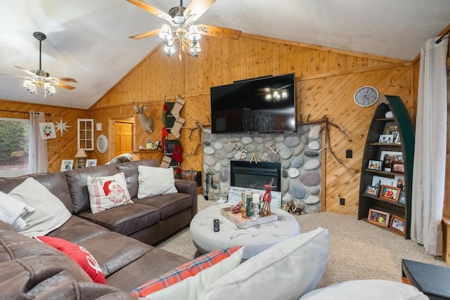 living area with carpet floors, a stone fireplace, wood walls, and vaulted ceiling