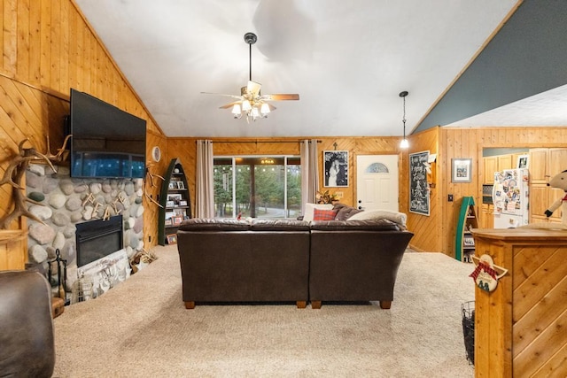 carpeted living room with ceiling fan, a stone fireplace, wood walls, and vaulted ceiling