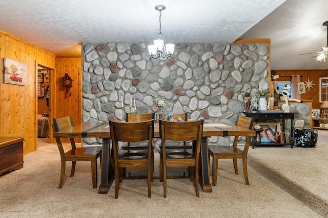 carpeted dining room with an inviting chandelier, wooden walls, and a textured ceiling