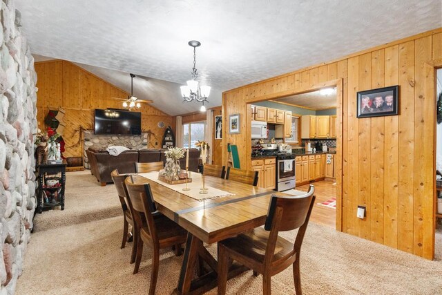 dining room with lofted ceiling, light colored carpet, wood walls, and a textured ceiling