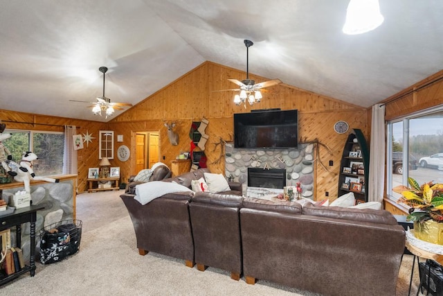 living area featuring a stone fireplace, carpet, wooden walls, and vaulted ceiling