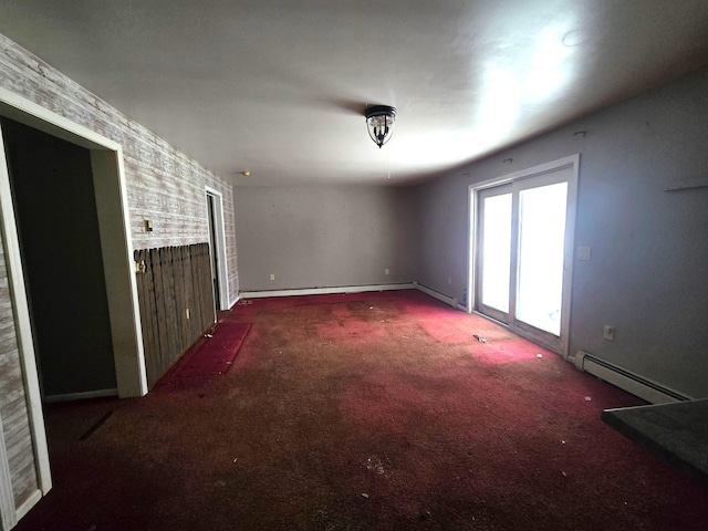 empty room featuring a baseboard heating unit and carpet floors