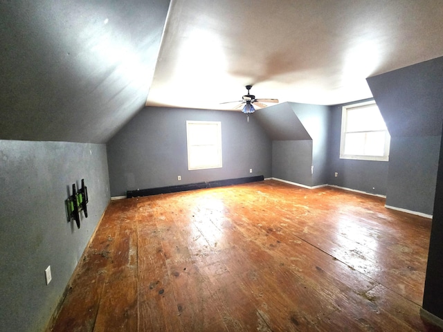 additional living space featuring a ceiling fan, baseboards, hardwood / wood-style flooring, vaulted ceiling, and a baseboard heating unit