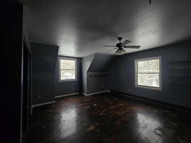 additional living space with baseboards, wood-type flooring, lofted ceiling, and ceiling fan