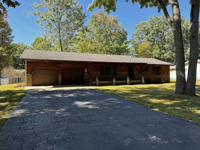 single story home with brick siding, fence, aphalt driveway, a front yard, and an attached garage