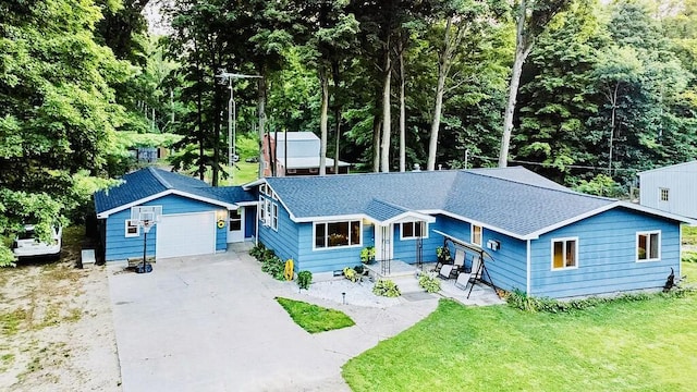 single story home with concrete driveway, an attached garage, a front yard, and roof with shingles