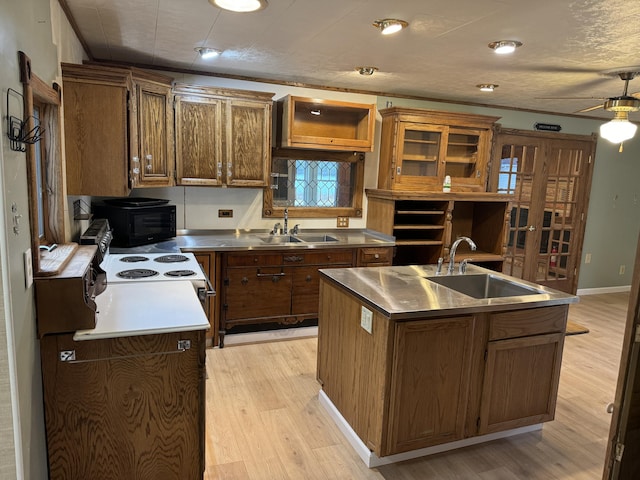 kitchen with a sink, stainless steel counters, light wood-style floors, and black microwave