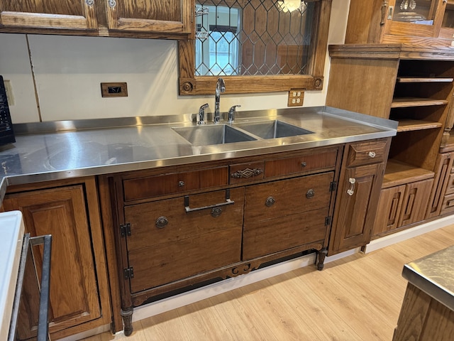 kitchen with open shelves, light wood-type flooring, stainless steel countertops, and a sink