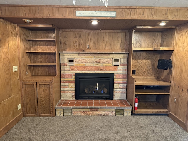 carpeted living room featuring wood walls and a fireplace