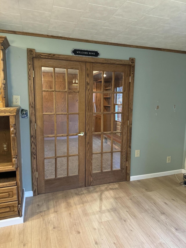 spare room featuring crown molding, wood finished floors, baseboards, and french doors