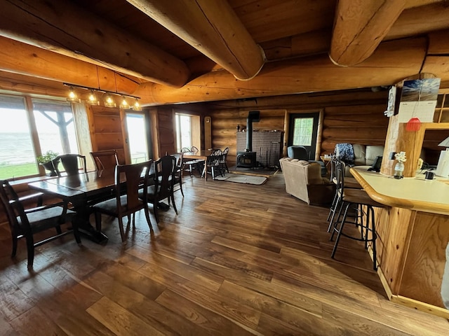 dining area with dark wood finished floors, beam ceiling, wood ceiling, and a wood stove