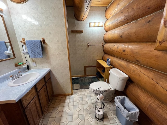 full bath featuring vanity, a tile shower, tile patterned flooring, toilet, and rustic walls