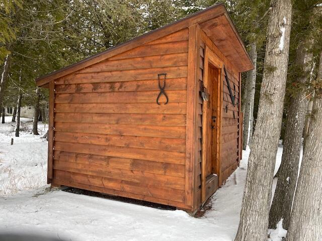 snow covered structure with an outbuilding